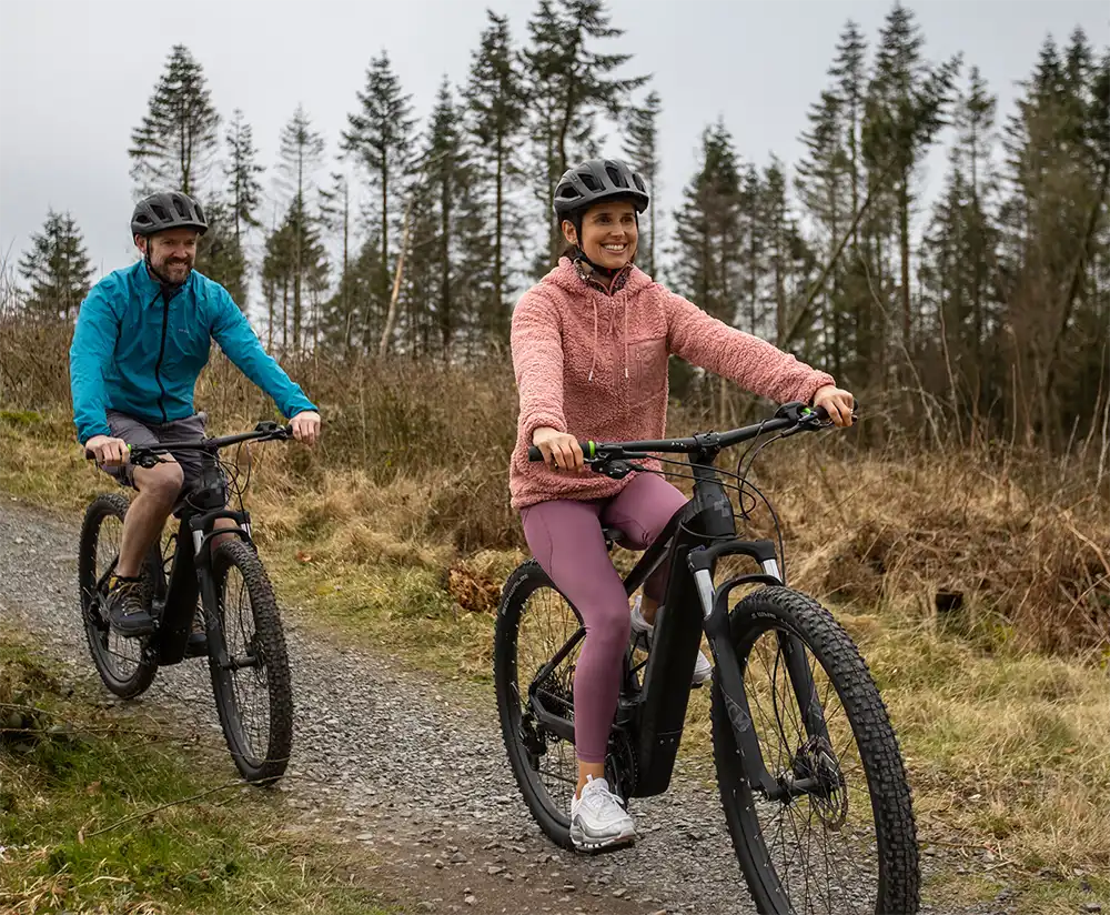 A couple cycling in forest trail